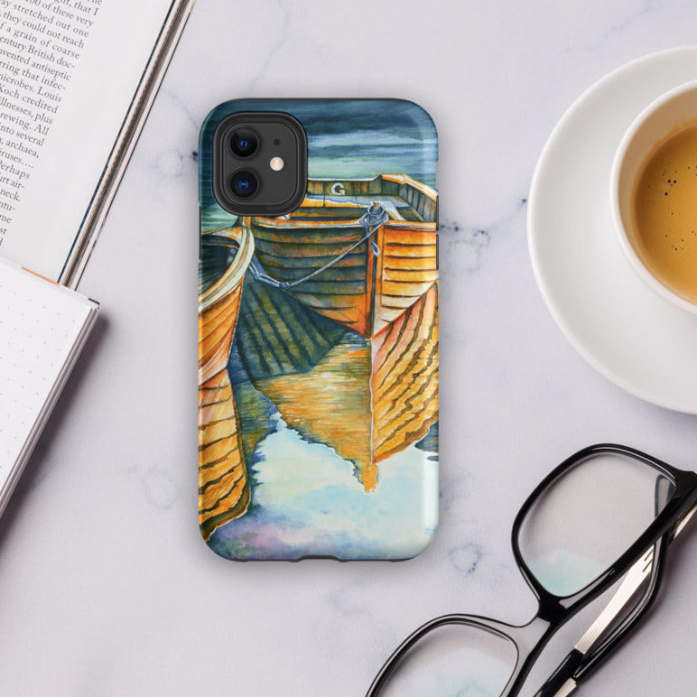 Phone case with a dock design on a marble surface with a book, pen, glasses, and coffee.
